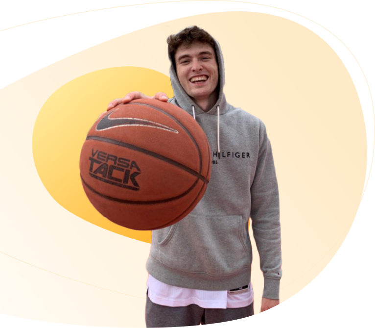 A man wearing a grey hoodie and playing with a basket ball